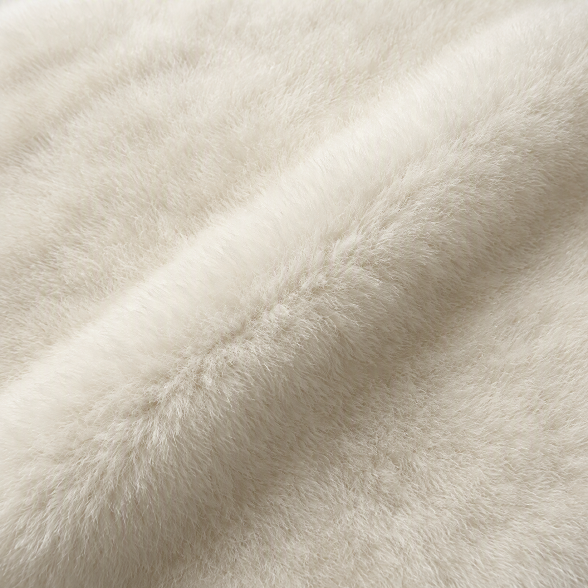 Close-up of ivory white baby alpaca fur showing its soft, fine texture and natural fiber direction