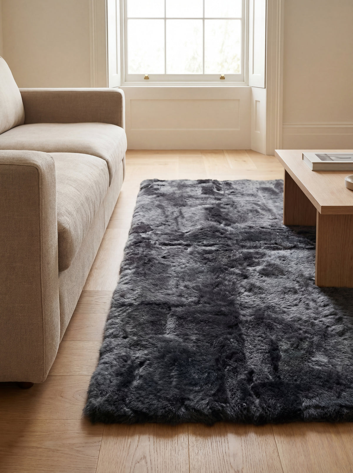 Charcoal baby alpaca fur area rug in a warm contemporary living room with light wood flooring