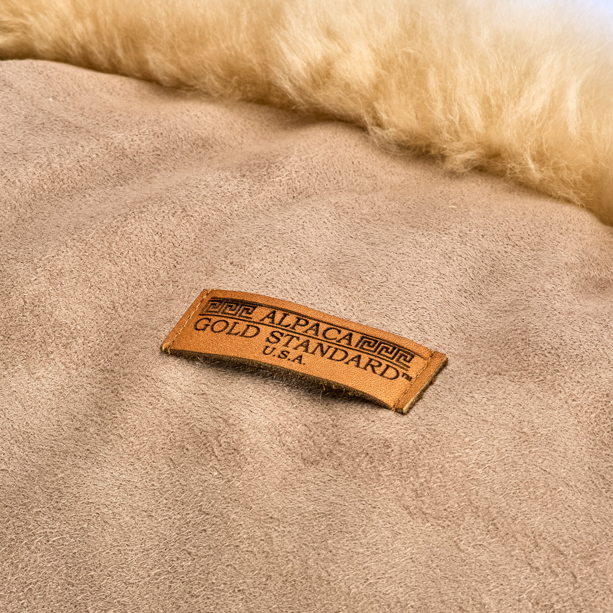 Back of beige baby alpaca fur cushion with Alpaca Gold Standard label