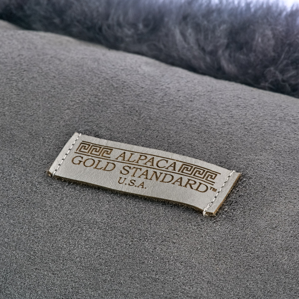 Back of dark gray baby alpaca fur cushion with Alpaca Gold Standard label