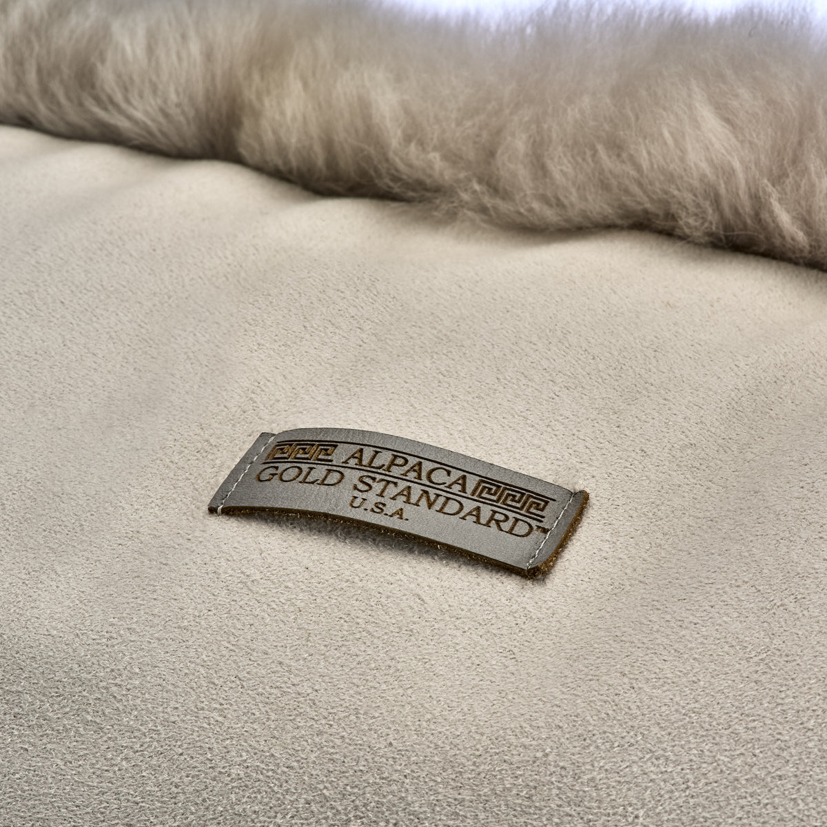 Back of light gray baby alpaca fur cushion with Alpaca Gold Standard label