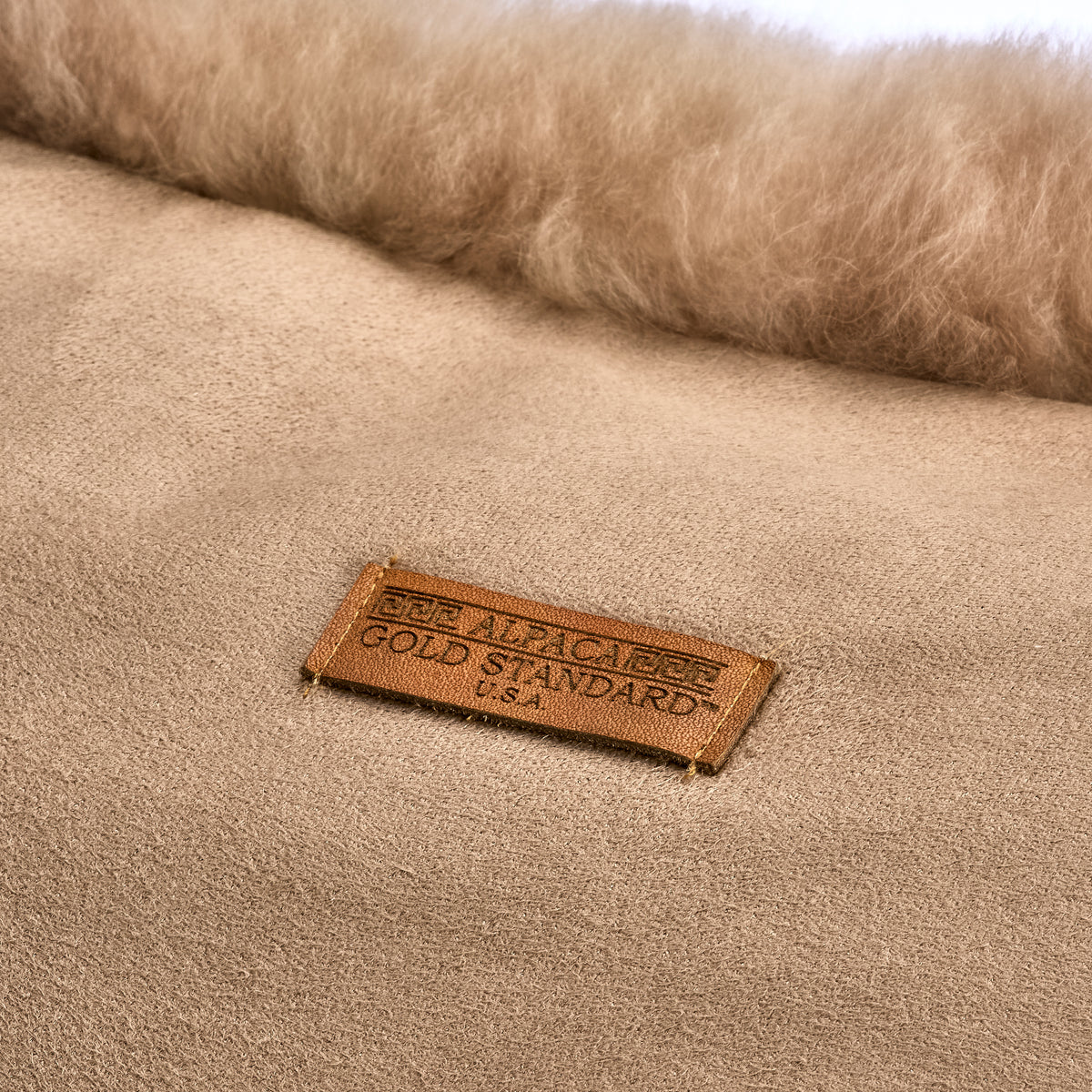 Back of taupe baby alpaca fur cushion with Alpaca Gold Standard label